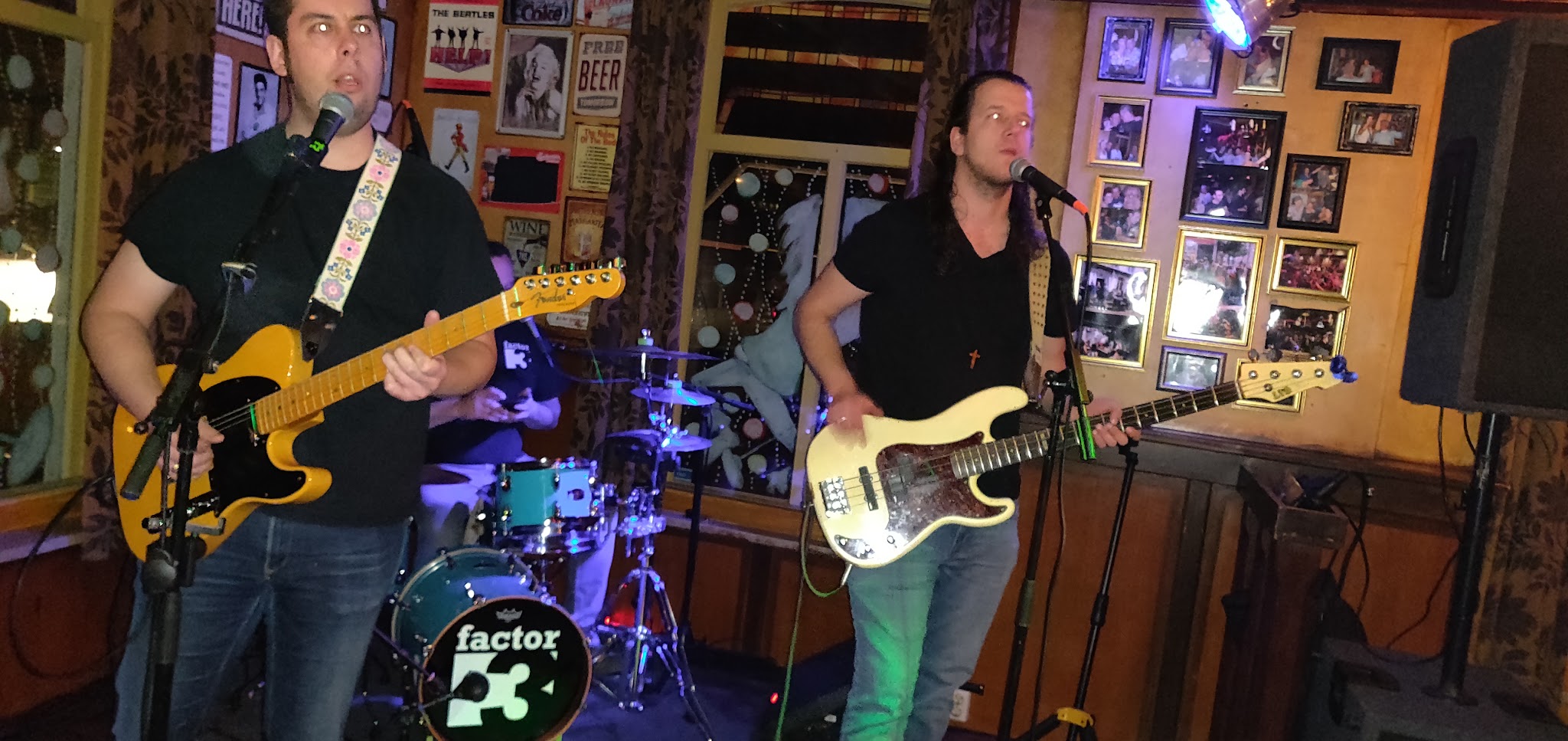 Een band speelt live in Café de Engel voor de wand met ingelijste foto's